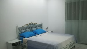 A bedroom with a bed, nightstands, a desk, and a window with curtains. - Superb villa near the sea (Houmt Souk)