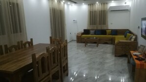 A living room with a wooden dining table, chairs, a sofa, and a coffee table. - Superb villa near the sea (Houmt Souk)