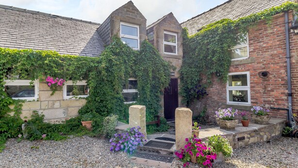 A traditional stone building with ivy-covered walls, a brick facade, and a gravel driveway. - The Granary (Morpeth)