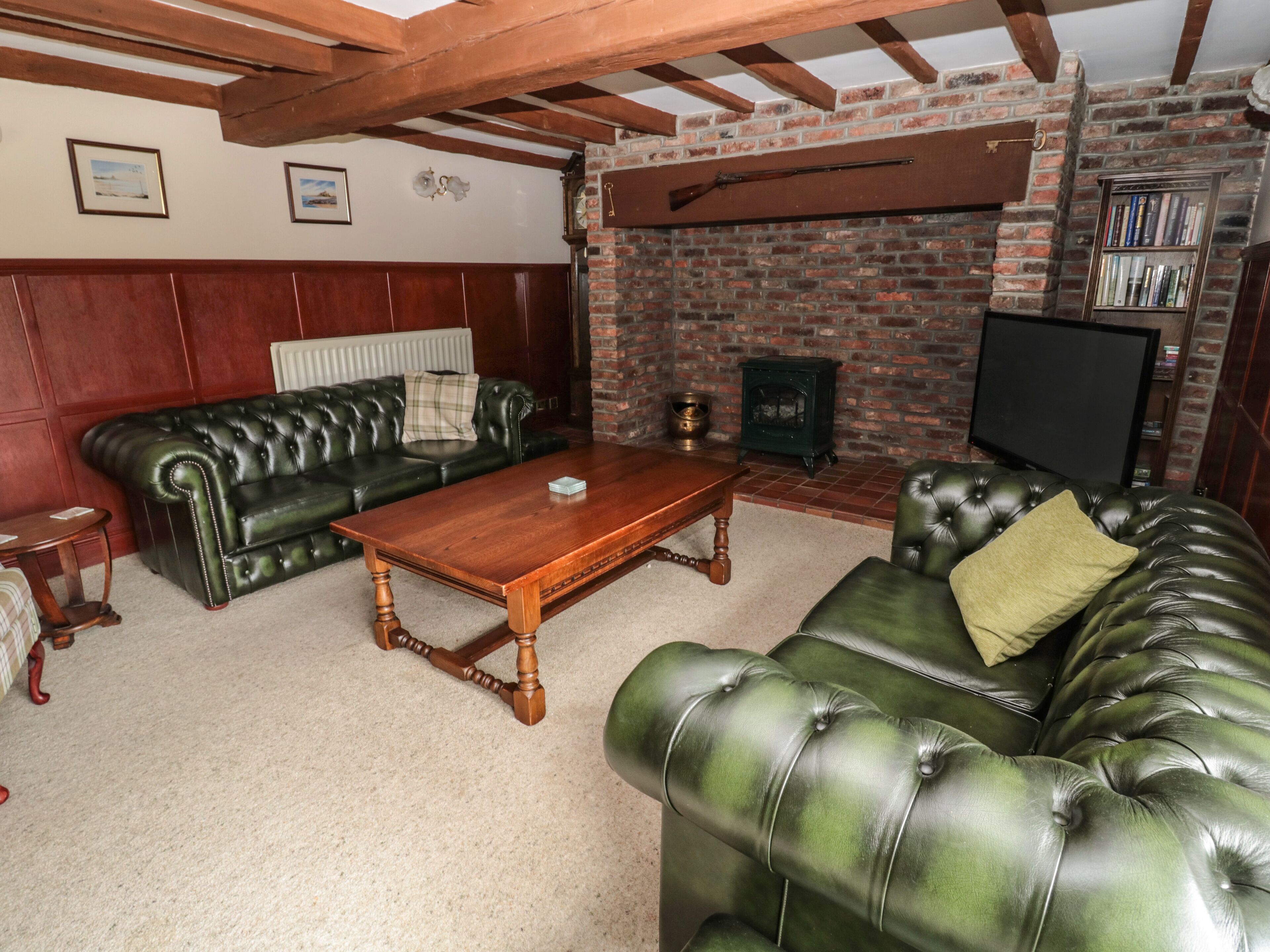 A living room with a fireplace, leather sofas, a wooden coffee table, and a television.