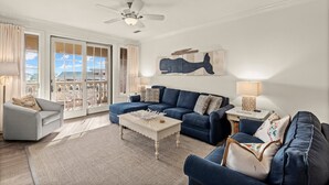 A spacious living room with a sectional sofa, a coffee table, and a ceiling fan. - The Village 3BR | Pool • Shops • Dining • Beach (Seacrest Beach)