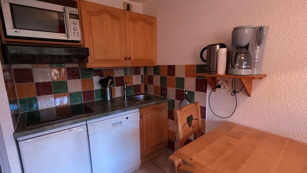Una cocina compacta equipada con microondas, lavavajillas y cafetera.