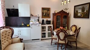 Un comedor con una mesa y sillas de madera, un mueble con puertas de vidrio y un televisor sobre un soporte.