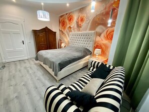 A bedroom with a bed, a sofa, a wooden wardrobe, and a wall with floral wallpaper.