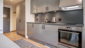 Una cucina moderna con mobili grigi, una cappa aspirante in acciaio inossidabile e un forno.