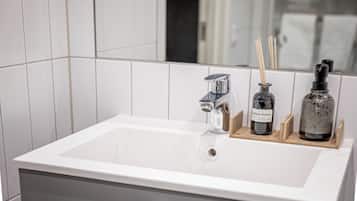A modern bathroom with a white sink, chrome faucet, and a mirror reflecting the room.