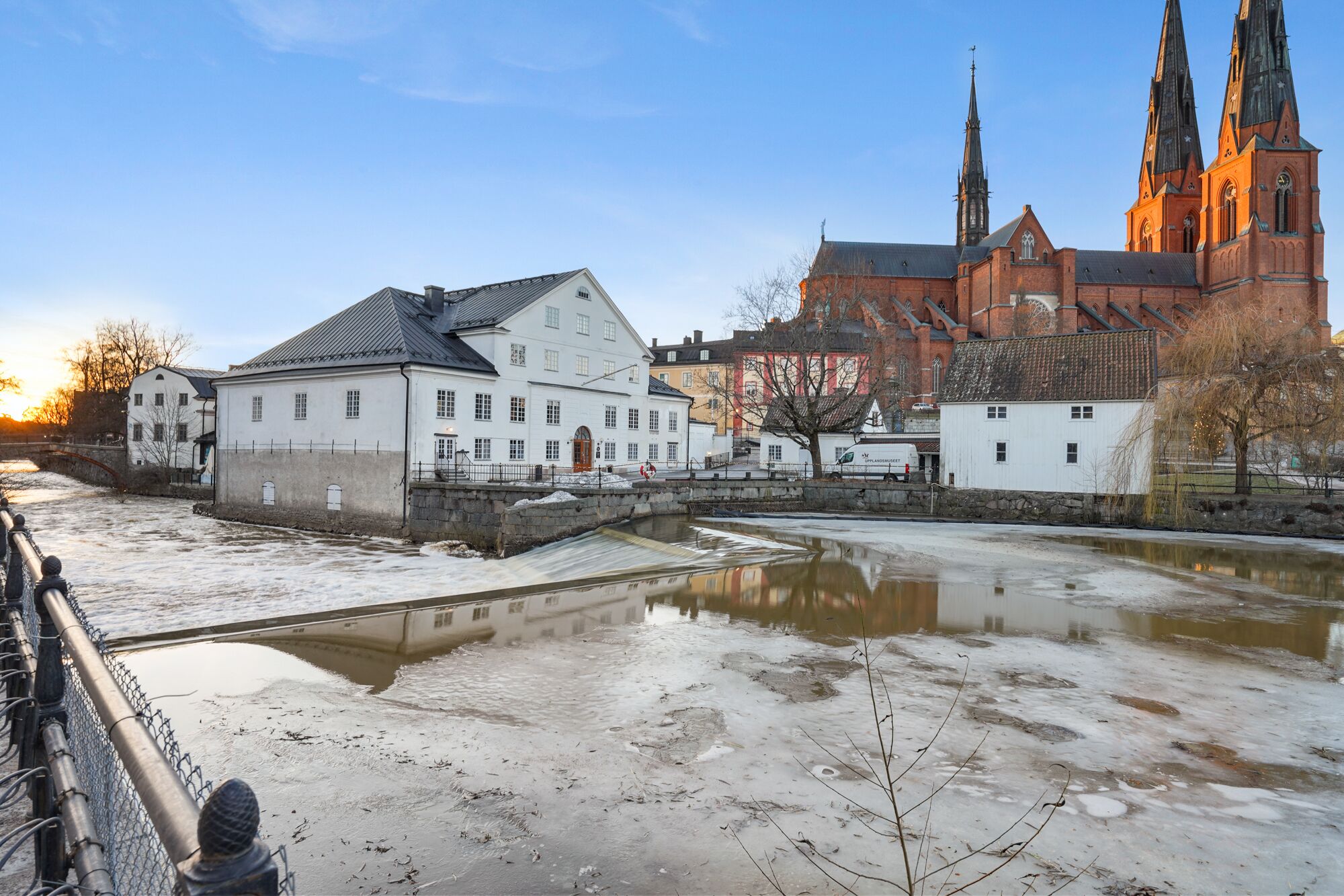 A riverside view with a historic building and a church in the background.