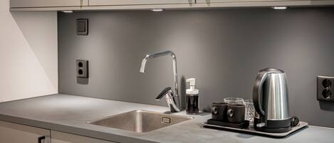 A modern kitchen with a stainless steel sink, a kettle, and a coffee machine.