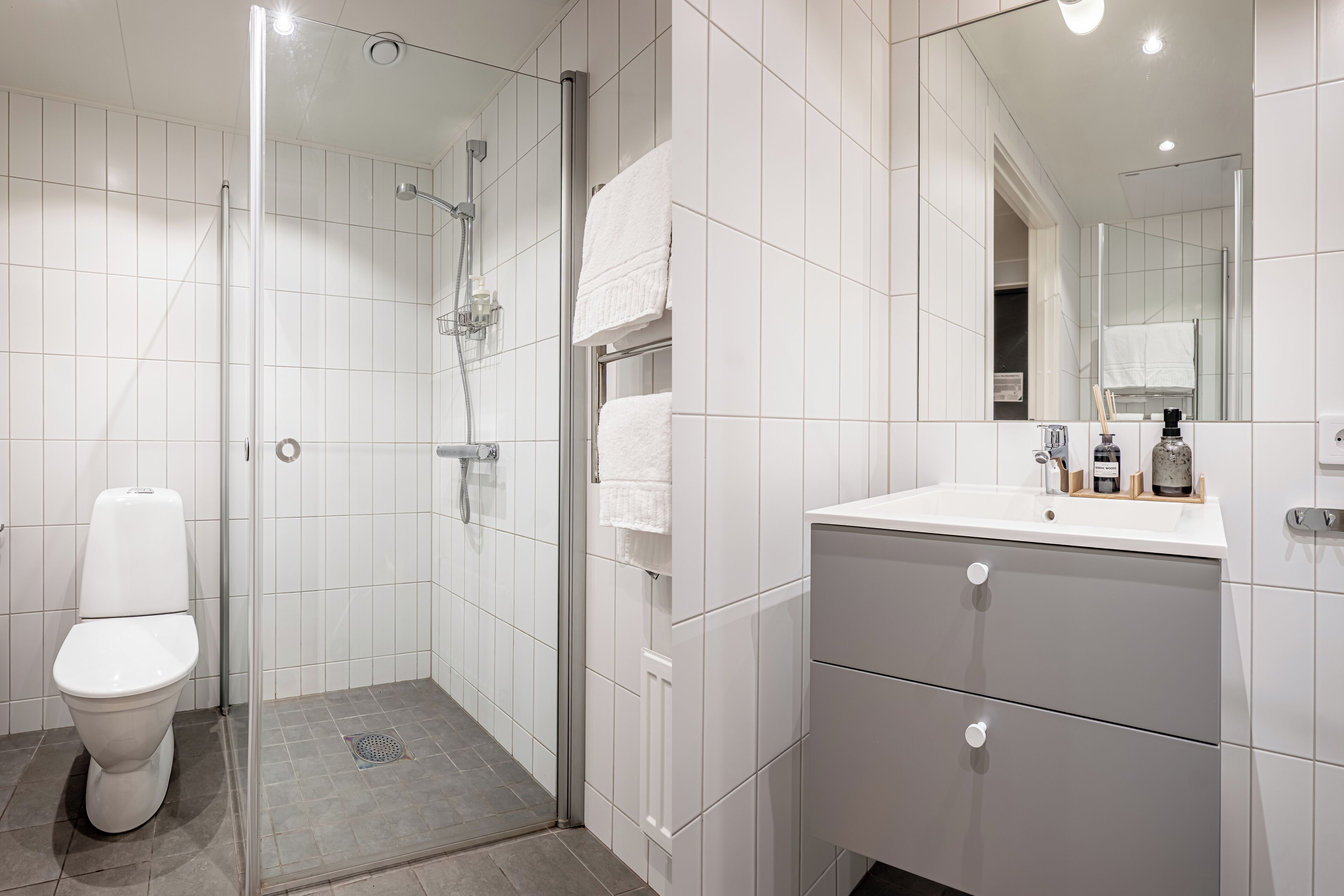 A modern bathroom with a toilet, shower, and vanity with a mirror.