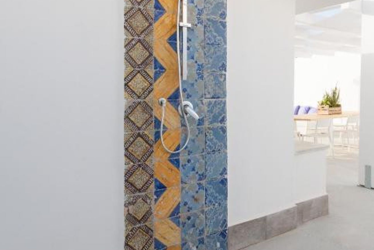 A bathroom with patterned tiles and a shower.