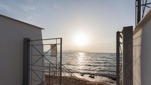 Blick auf das Meer von einem überdachten Gang mit einem Metallgitter zum Strand.