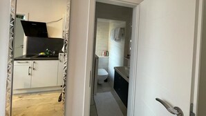Ein schmaler Flur mit einer Küche links und einem Badezimmer rechts.