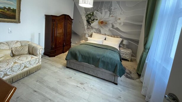 Ein Schlafzimmer mit einem Bett, einer Couch, einem Holzschrank und einem Wandbild.