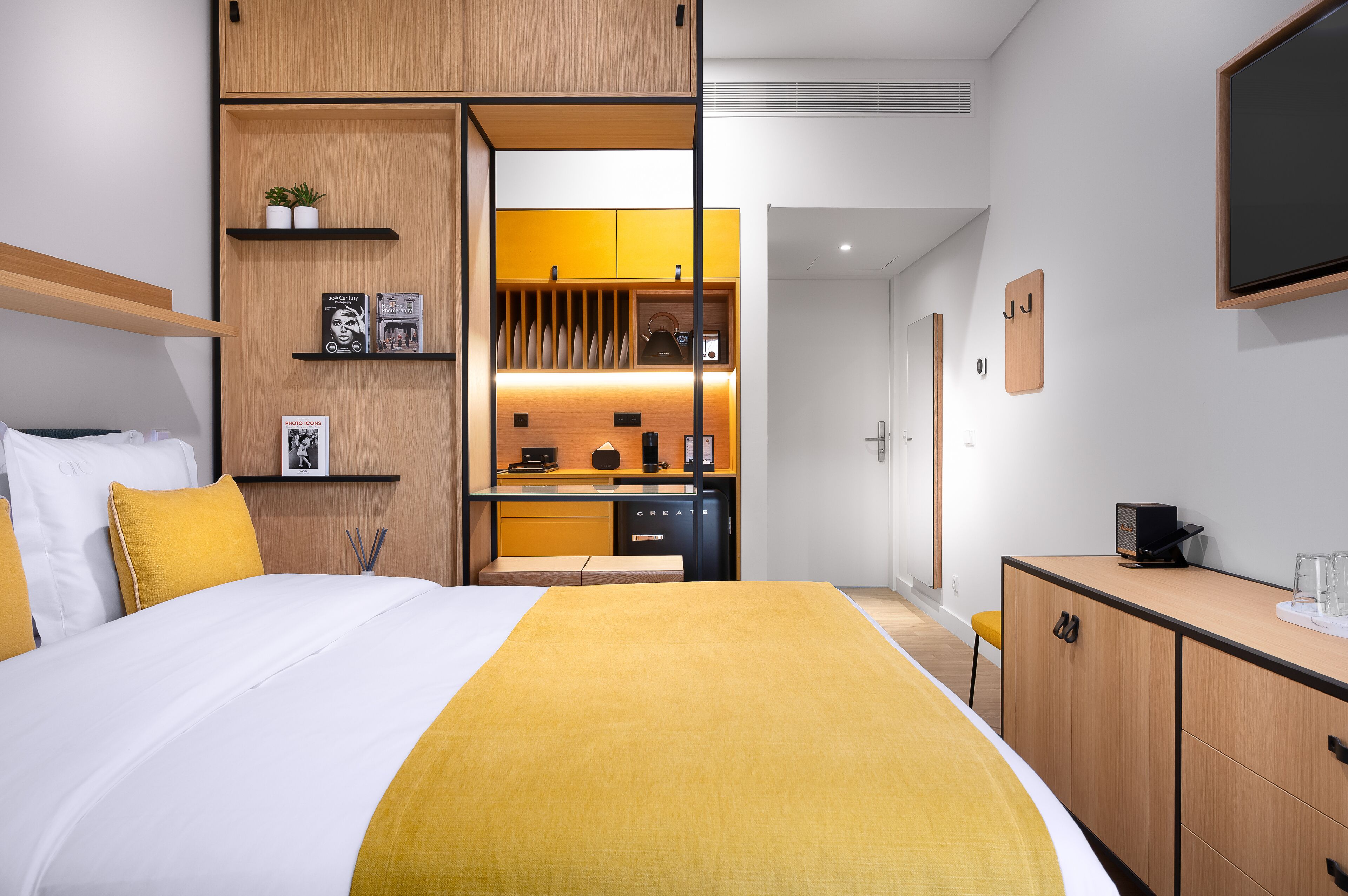 Una habitación de hotel moderna con una cama, un escritorio y una kitchenette.