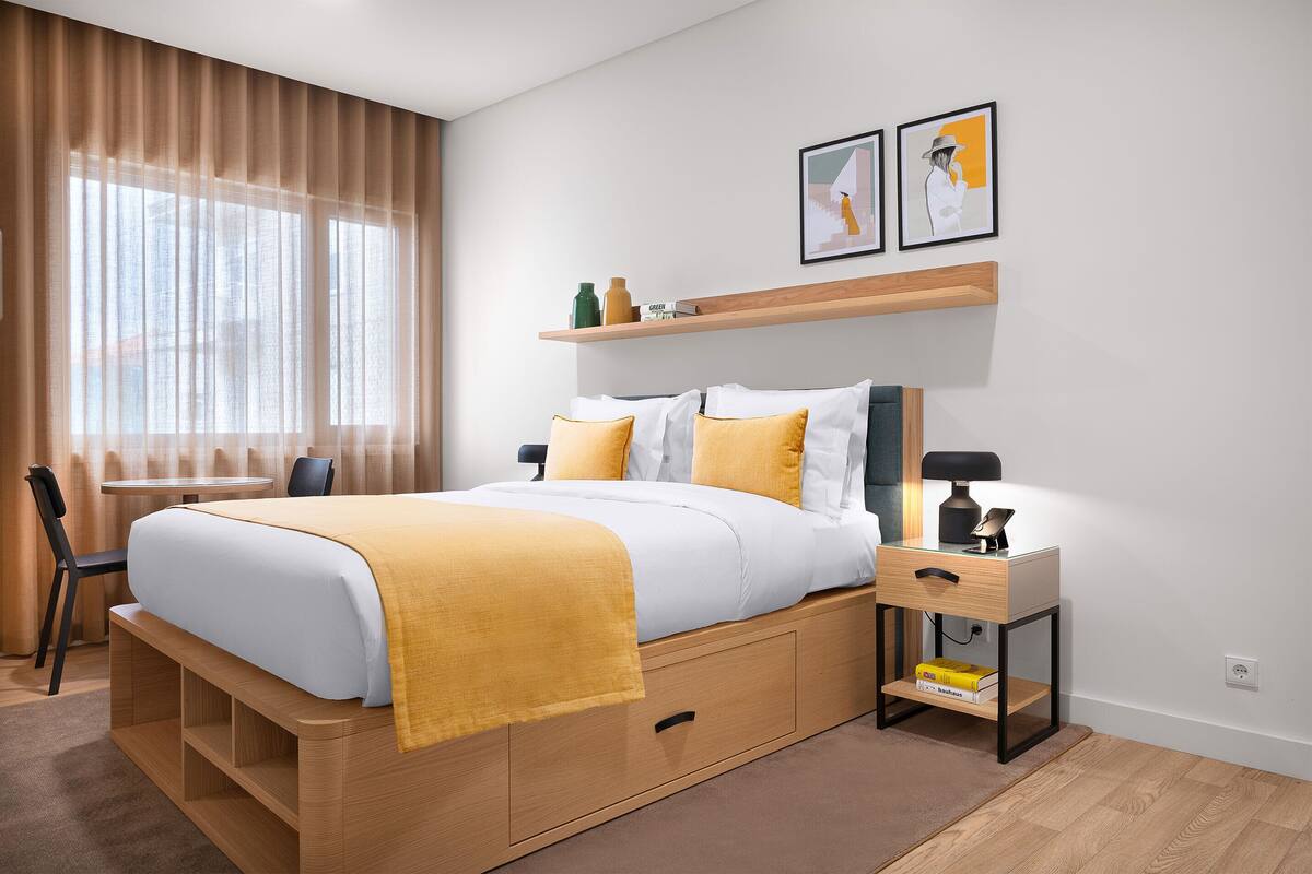 A modern bedroom with a bed, bedside table, and a desk with a chair.