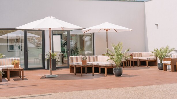 Un espace extérieur aménagé en terrasse, avec des sièges, des parasols et des plantes en pot.