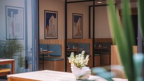 Un intérieur moderne avec des tables en bois et des sièges rembourrés bleus. Des œuvres d’art encadrées ornent les murs.