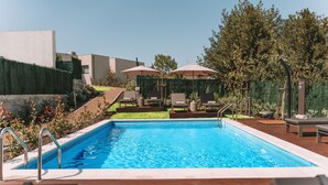 Une piscine rectangulaire à l’eau d’un bleu limpide, entourée de chaises longues et de parasols.