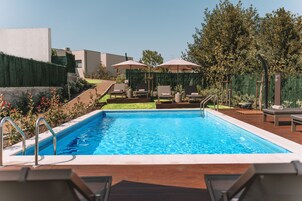 Una piscina al aire libre de temporada, sombrillas, tumbonas