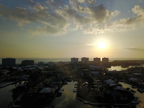 A coastal cityscape at sunset with buildings, a marina, and a body of water. - Beachfront 2BR/2BA condo with pool, wifi, and balcony on Marco Island. (Marco Island)