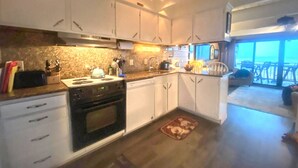 A compact kitchen with white cabinets, a built-in oven, and a small island with a sink.
