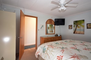 A bedroom with a bed, a television, a ceiling fan, and artwork on the walls. - Cute, cozy one bedroom, one bath condo with an oceanfront balcony, so come and enjoy beautiful ocean views! (Ocean City)