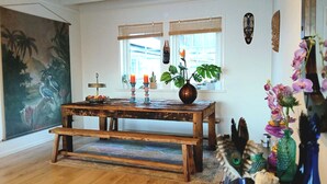 Una mesa de madera rústica con velas, un florero con una planta y un cuadro de pájaros en la pared.