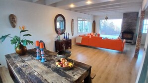 Un salón amplio con una mesa de comedor de madera, una chimenea y un sofá color naranja brillante.