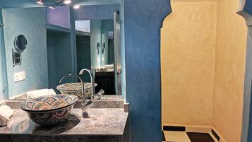 Un bagno con un ampio specchio, un lavabo e una doccia con pavimento a scacchi.