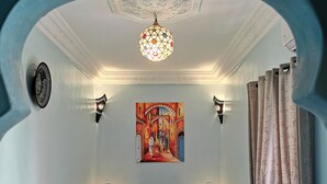 A room with a bed, two black pillows, a painting, a chandelier, and a patterned rug. - Close to everything in the medina - Authentic renovated Moroccan house (Marrakech)