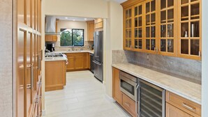 A modern kitchen with wooden cabinets, stainless steel appliances, and a large window.