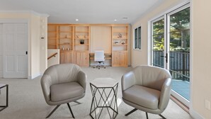 A modern living room with two leather chairs, a hexagonal coffee table, and built-in wooden shelving.