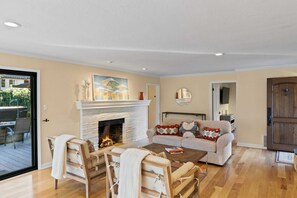 A living room with a fireplace, a sofa, a coffee table, and a dining area with chairs.