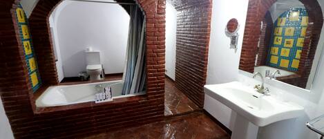 A bathroom with a bathtub, a sink, and a mirror.