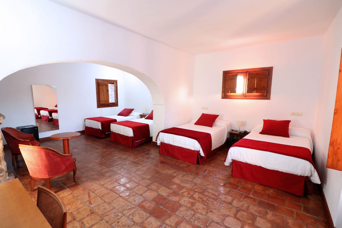 Une chambre d’hôtel avec trois lits, une table à manger et des chaises.