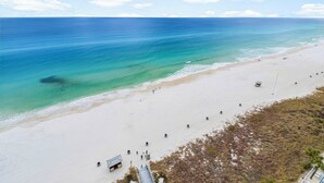 A beach with clear turquoise water, sandy shore, and a few people walking. - Splash 2002E BEAUTIFUL UNIT WITH GREAT VIEWS! (Panama City Beach)