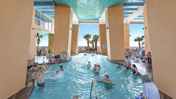 An indoor swimming pool with multiple lanes and people swimming and playing. - Splash 2002E BEAUTIFUL UNIT WITH GREAT VIEWS! (Panama City Beach)