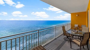 A balcony with a glass table and chairs, overlooking a beach with the ocean and a clear sky. - Splash 2002E BEAUTIFUL UNIT WITH GREAT VIEWS! (Panama City Beach)