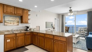 A modern kitchen with wooden cabinets, a large island, and a view to the outside. - Splash 2002E BEAUTIFUL UNIT WITH GREAT VIEWS! (Panama City Beach)