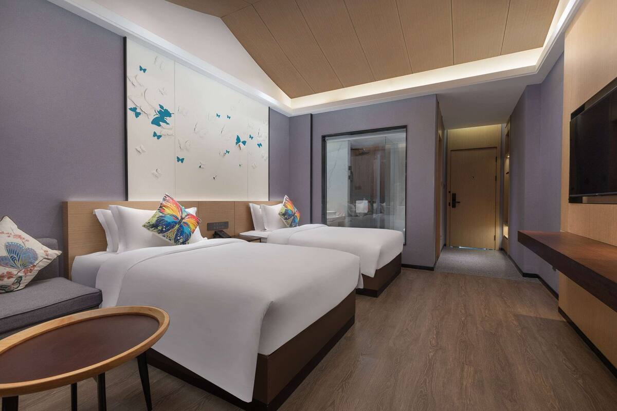 Une chambre d’hôtel avec deux lits, un canapé, une petite table et un téléviseur.