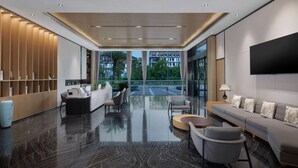 A modern lobby with a reflective floor, seating area, and a large TV screen. - Ramada by Wyndham Guilin Yangshuo Resort (Guilin)