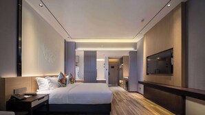 A modern hotel room with a large bed, bedside tables, a TV, and a wooden floor. - Ramada by Wyndham Guilin Yangshuo Resort (Guilin)