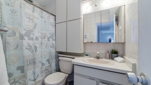 Bagno con WC, lavandino, specchio e tenda da doccia a tema nautico.