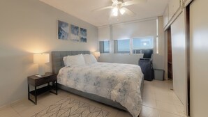 Una camera da letto con un letto, un comodino, una lampada, una ventola a soffitto e un'opera d'arte appesa al muro.