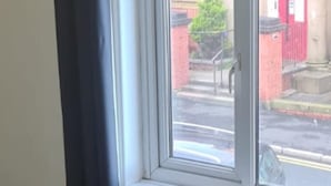 A window with a view of a street, a black curtain, and a white wall. - Lovely 2-bed House in Bolton Greater Manchester (Bolton)