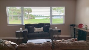 Ein Wohnzimmer mit grauem Sofa, einem Couchtisch und einem Fenster mit Jalousien.