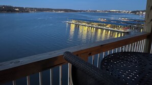 A view from a balcony overlooking a calm body of water with docks and buildings in the distance.