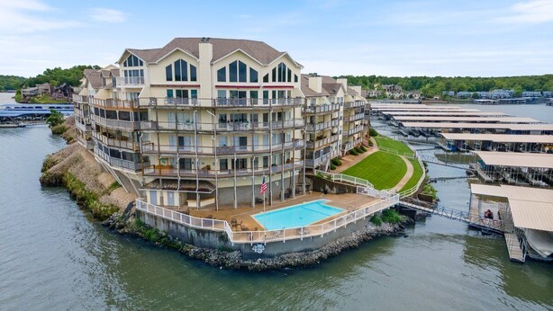 A waterfront hotel with multiple balconies, a swimming pool, and a dock area.