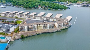 An aerial view of a waterfront hotel with multiple buildings, a dock, and a marina.