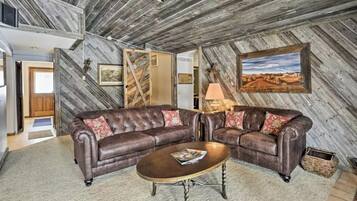 A rustic living room with a leather sectional sofa, a wooden coffee table, and a framed landscape painting on the wall.